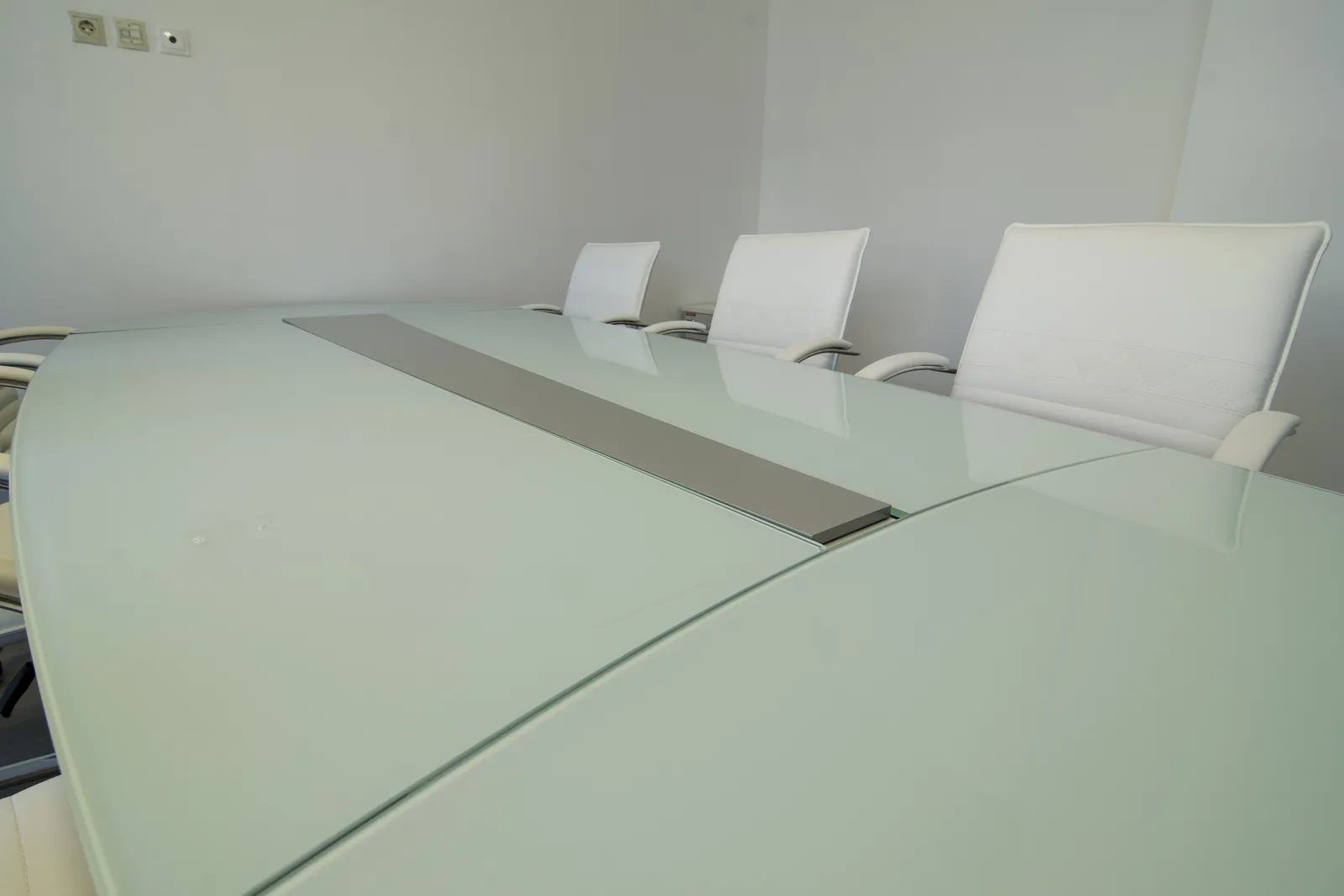 Before: white glass conference table photographed in a bare room